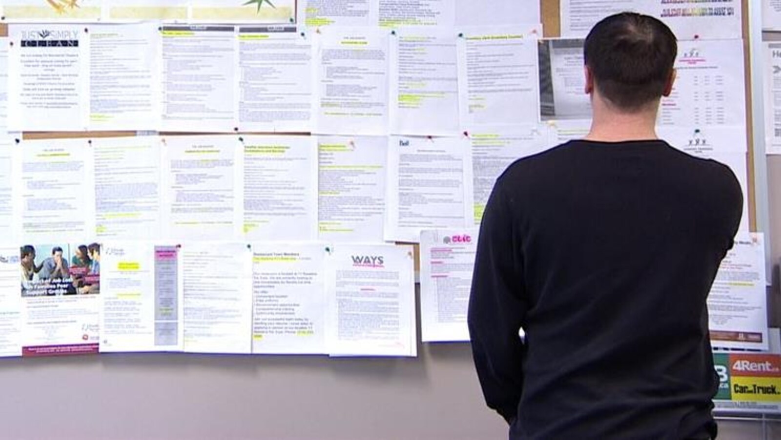 Un chômeur examine des offres d'emploi sur un babillard