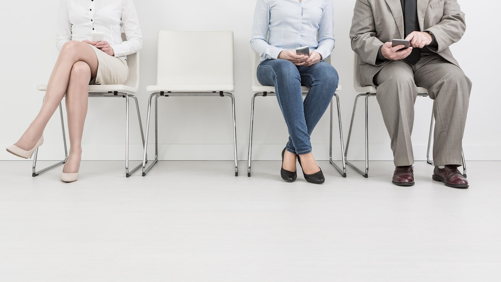 Trois personnes sont assises sur des chaises enlignées contre un mur.