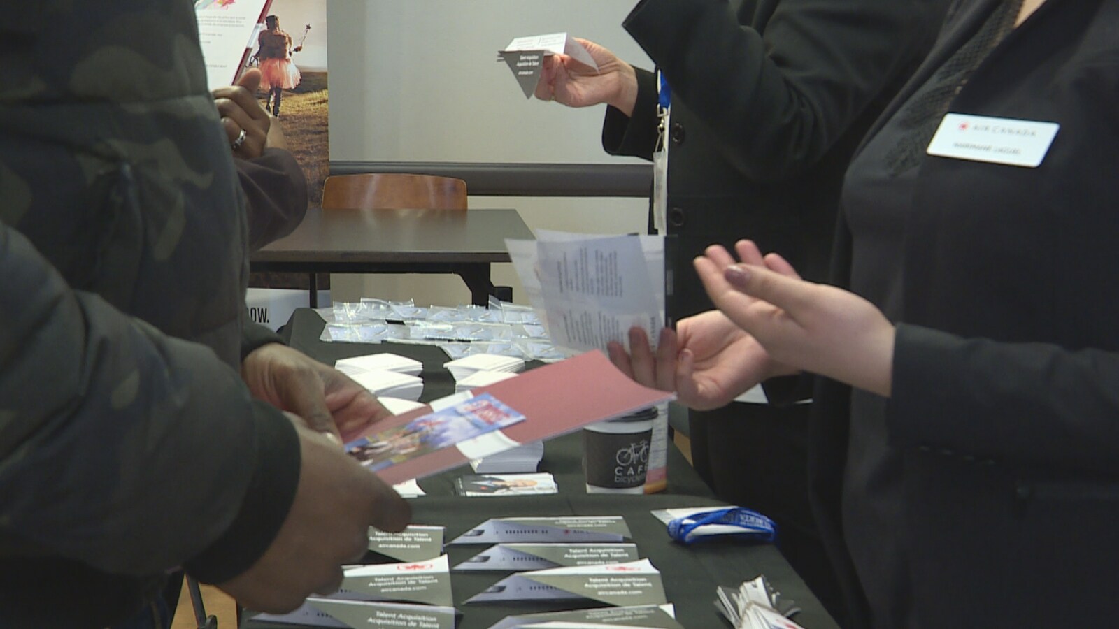 Des employeurs et des employés potentiels s'échangent des documents.