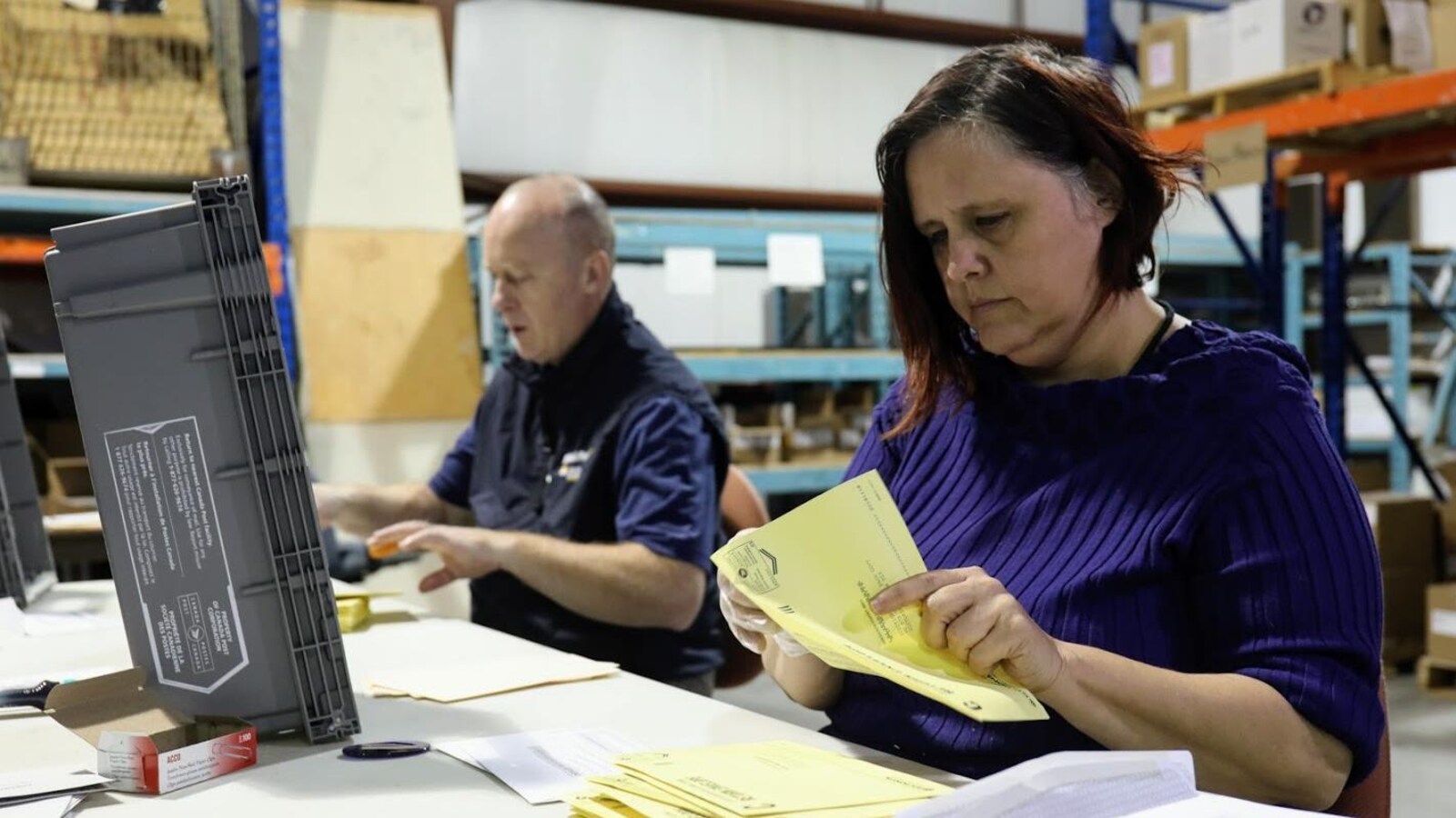 Des employés sont assis et ouvrent des enveloppes.