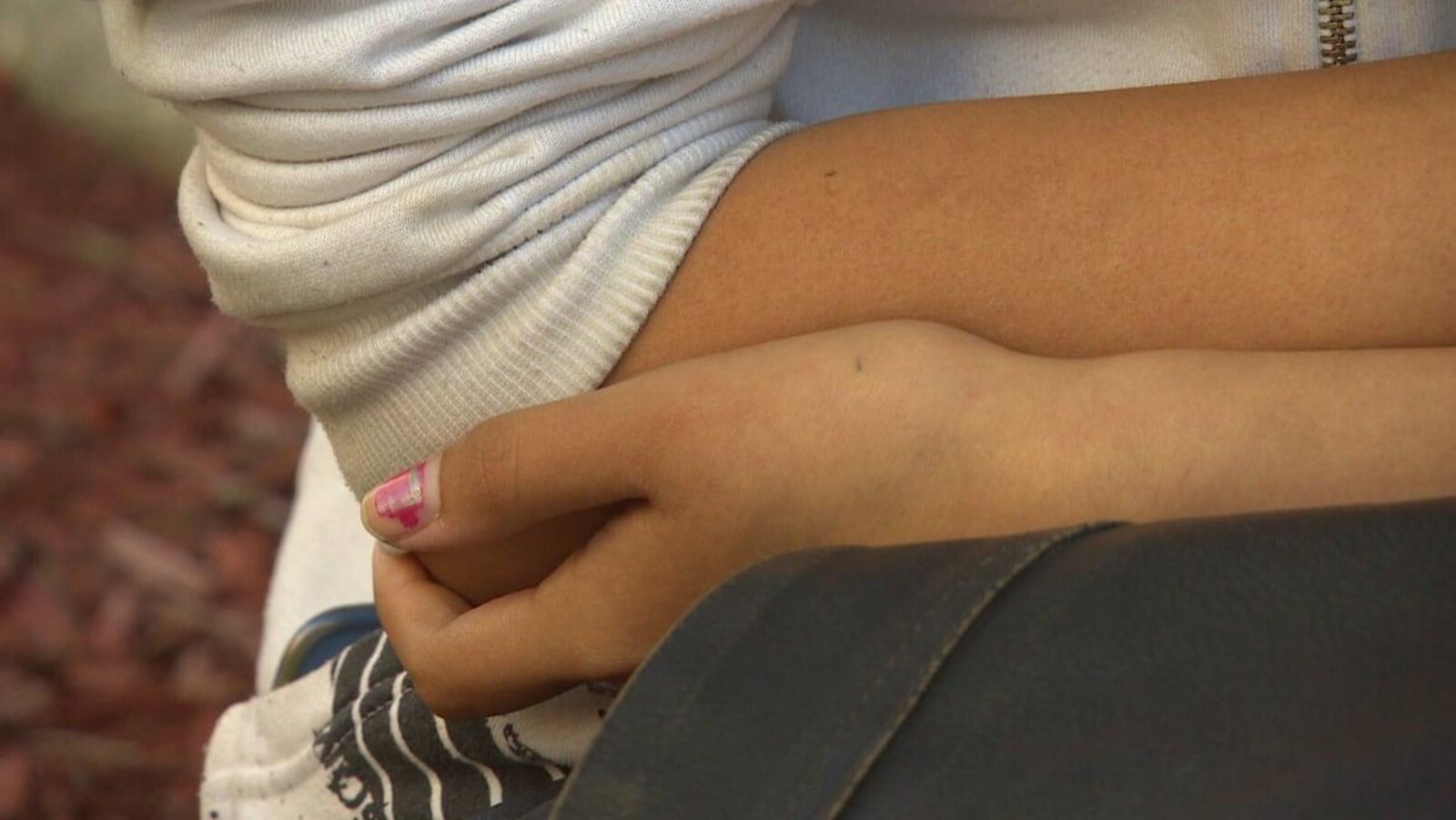 Une adolescente se tient le coude.