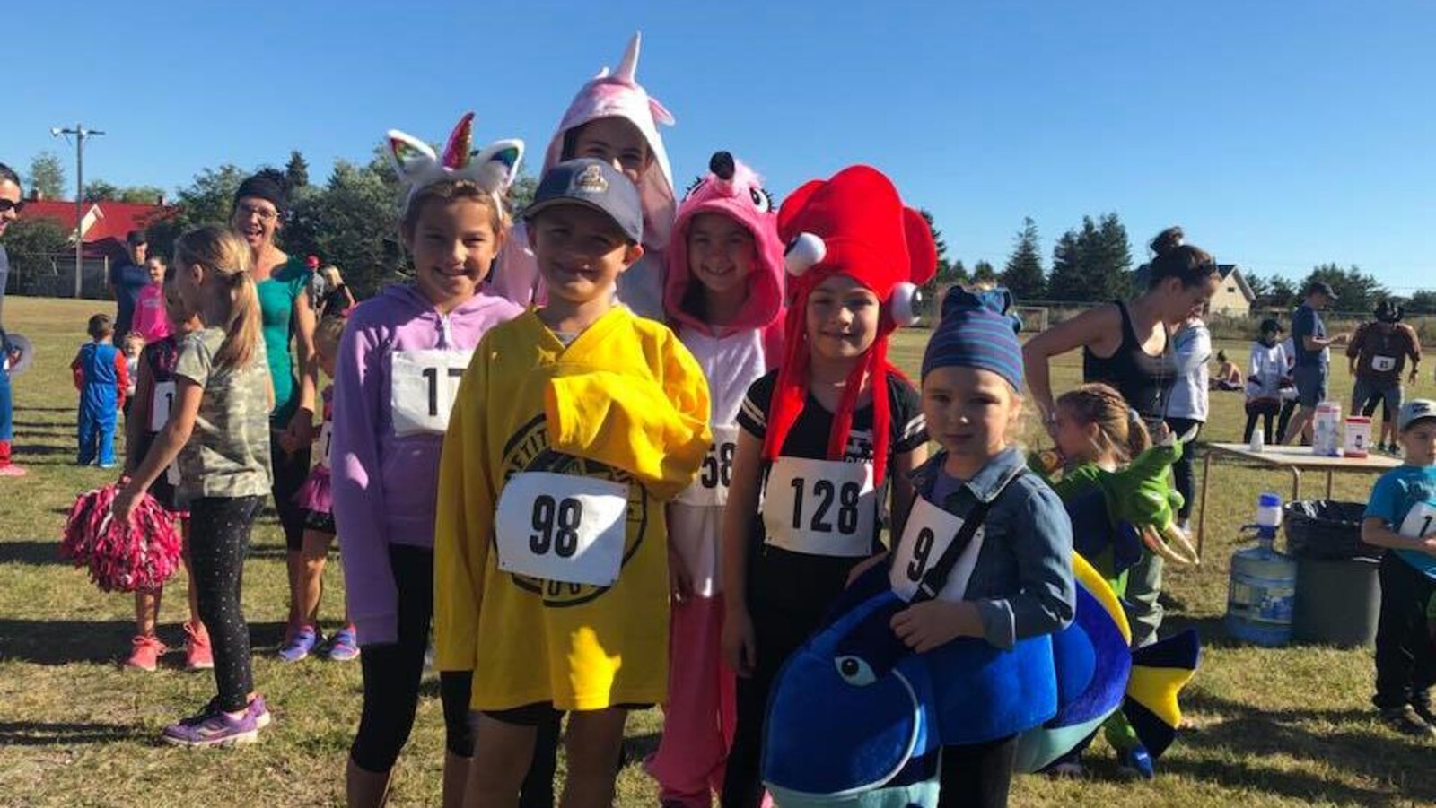 Des enfants costumés en poisson, en licorne et en homard portent un dossard.