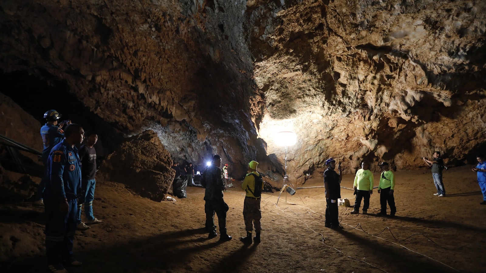Une dizaine de personnes qui forment l'équipe de sauvetage se trouvent dans une grotte. Certains portent des lampes de poche.