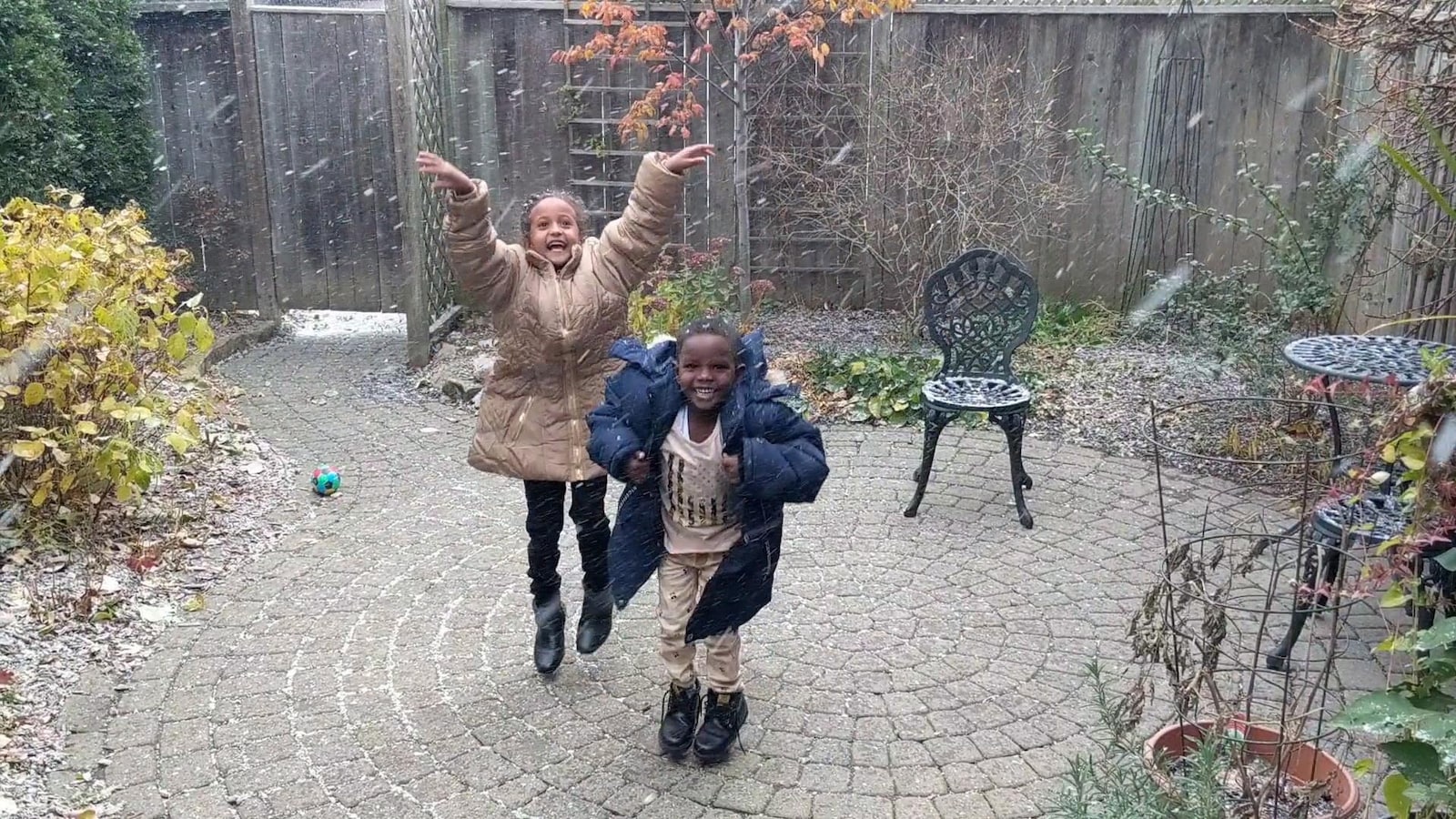 Deux jeunes enfants qui dansent dans la neige.