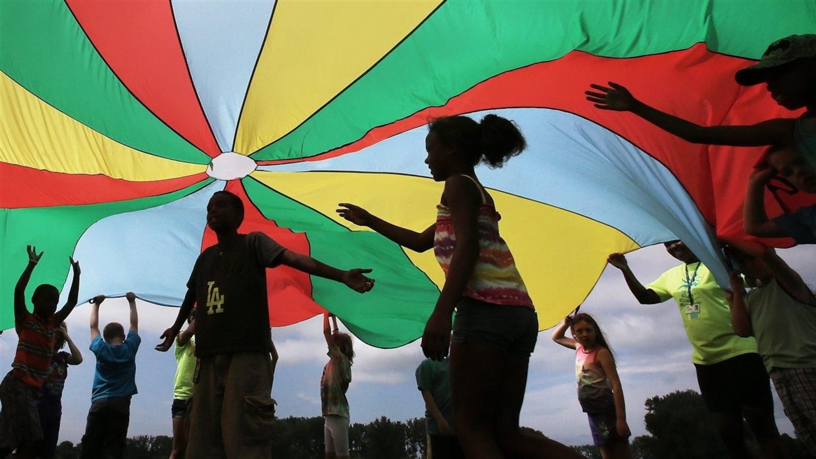 Des enfants jouent sous un grand chapiteau de tissu coloré.