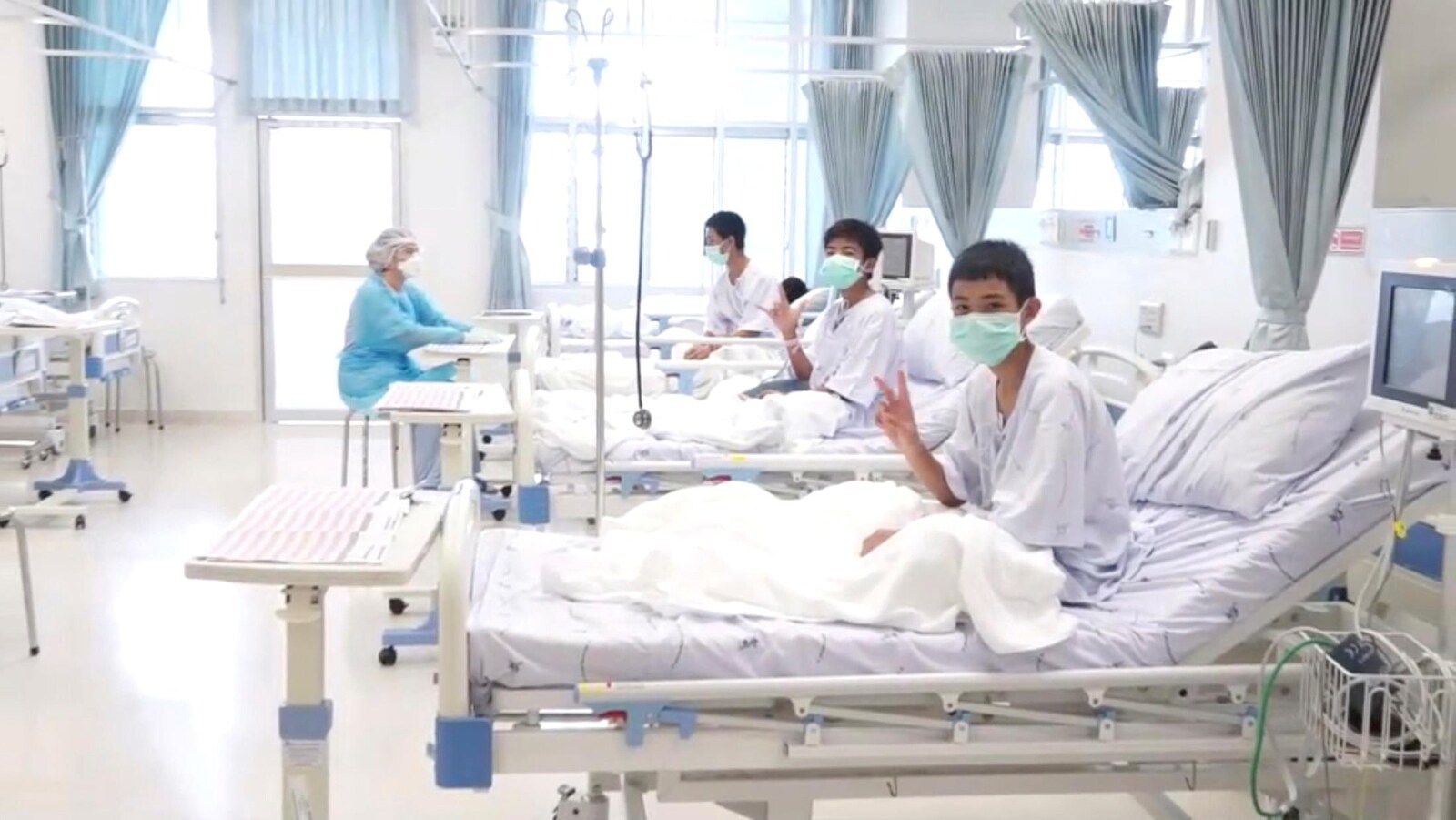 Trois des 12 garçons rescapés posent dans une chambre d'hôpital en Thaïlande.