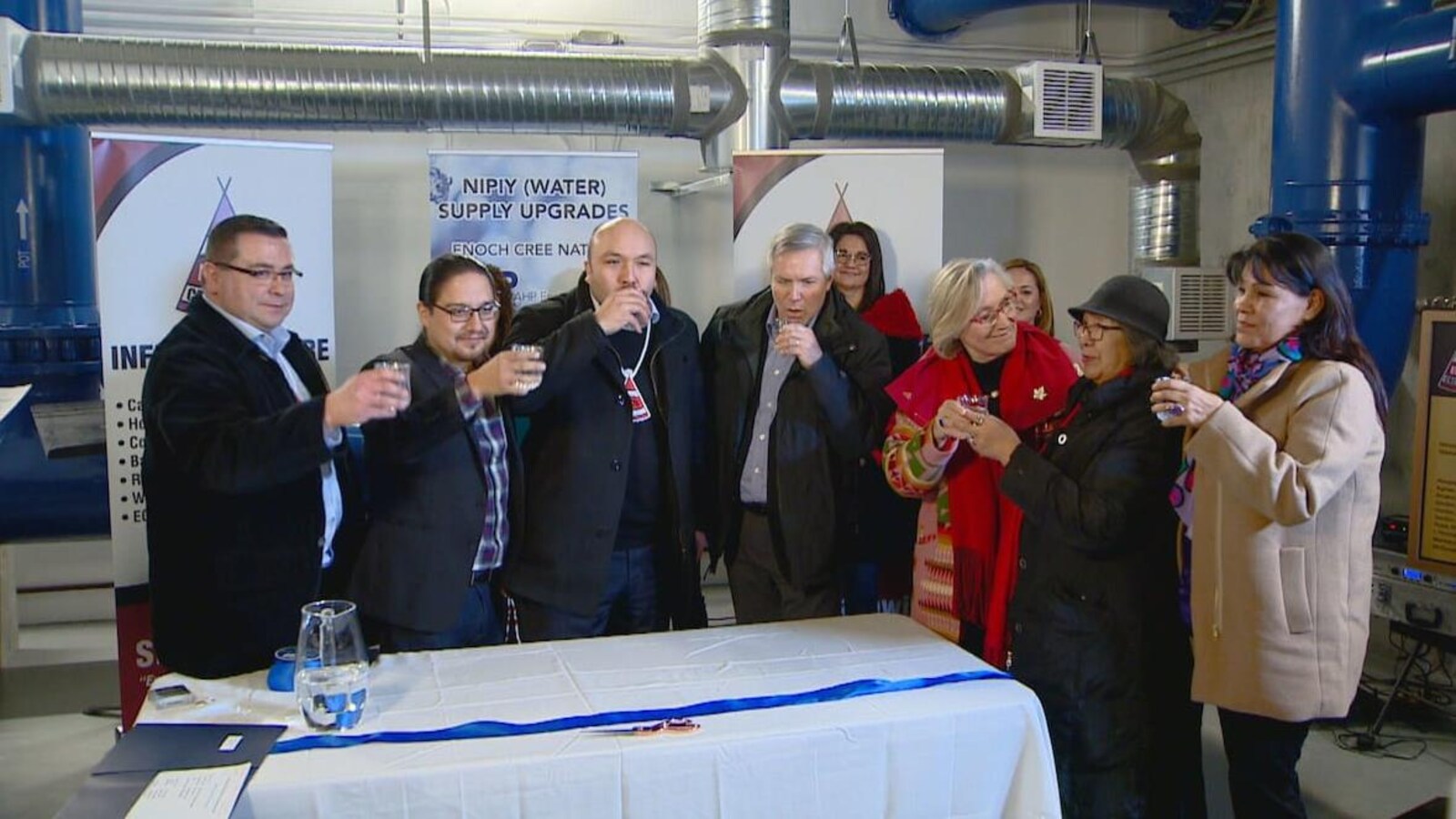 Des représentants de la communauté d'Enoch et du gouvernement fédéral boivent un verre d'eau pour souligner l'inauguration de la nouvelle usine.