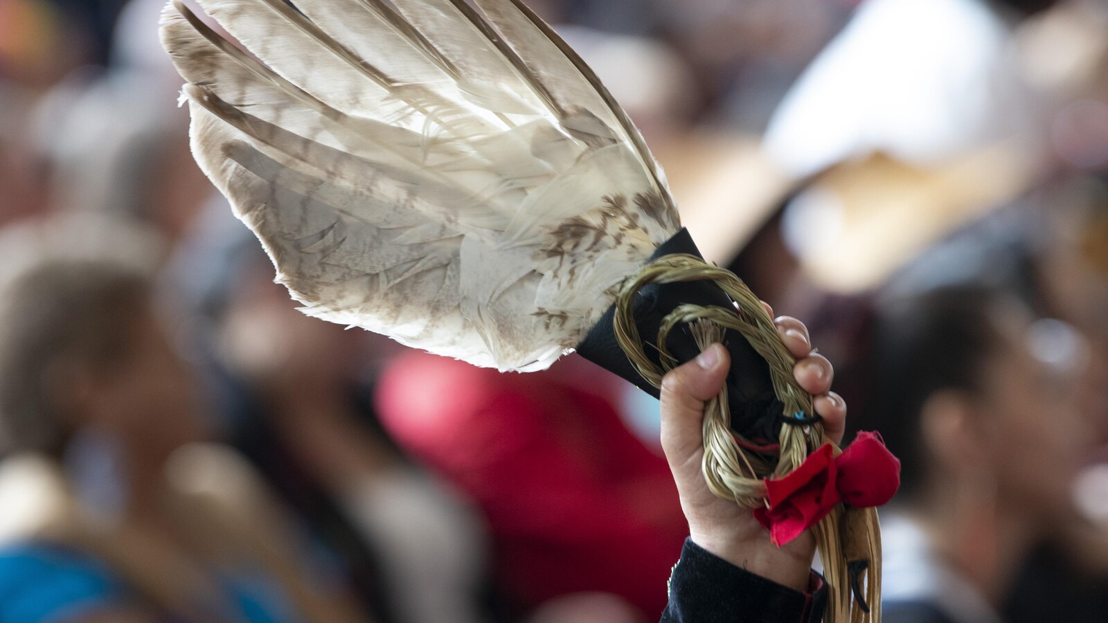 Un ruban rouge attaché à une plume d’aigle blanche a été levé dans les airs par un membre de l’assistance lors de l’événement.