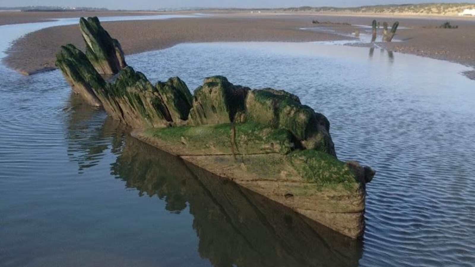Une partie de la coque en bois sortant du sable