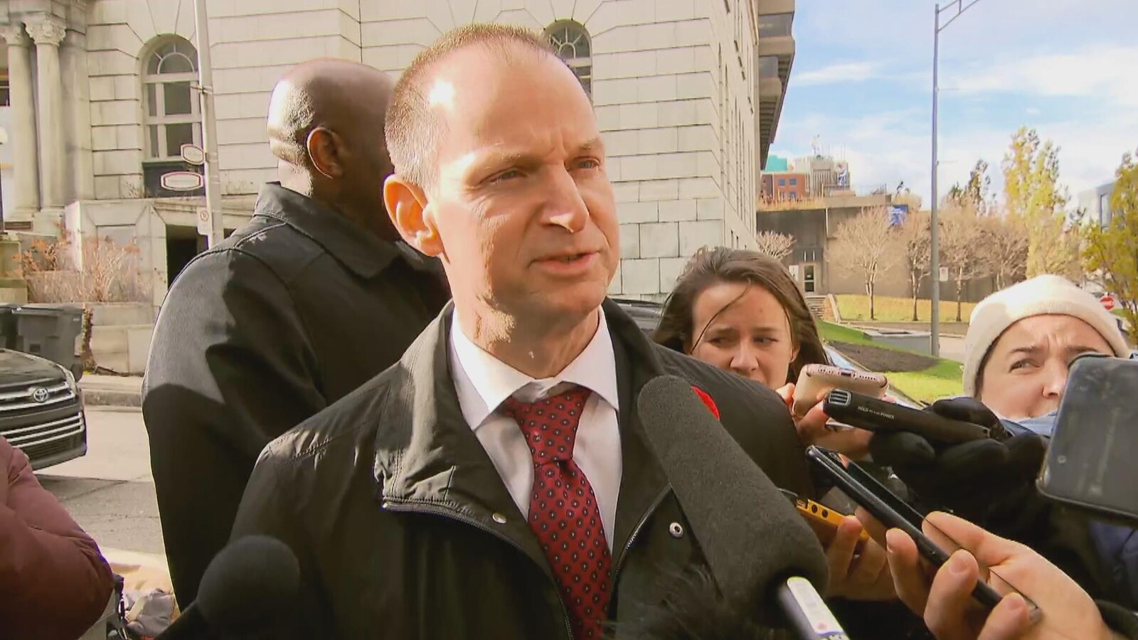 Le ministre des Finances Éric Girard face aux micros des journalistes.