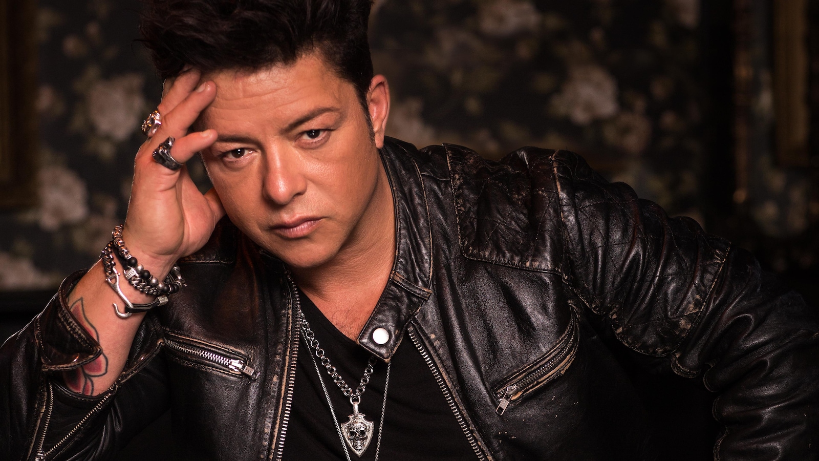 Le chanteur prend la pose dans son éternel veston de cuir, les bagues aux doigts.