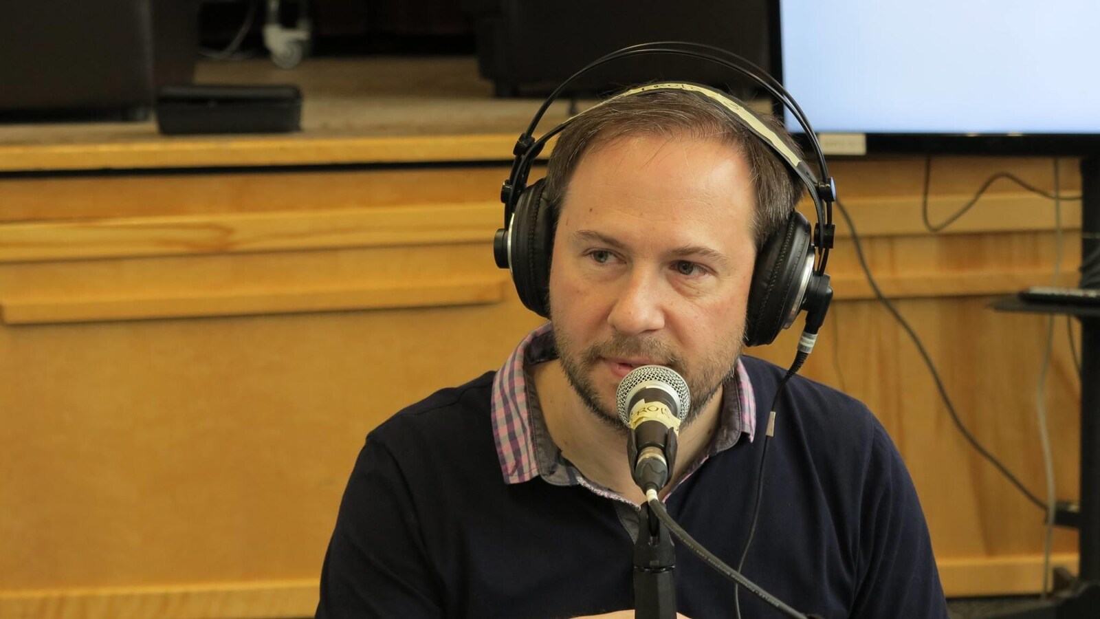 Éric dans un studio de radio avec des écouteurs sur les oreilles.