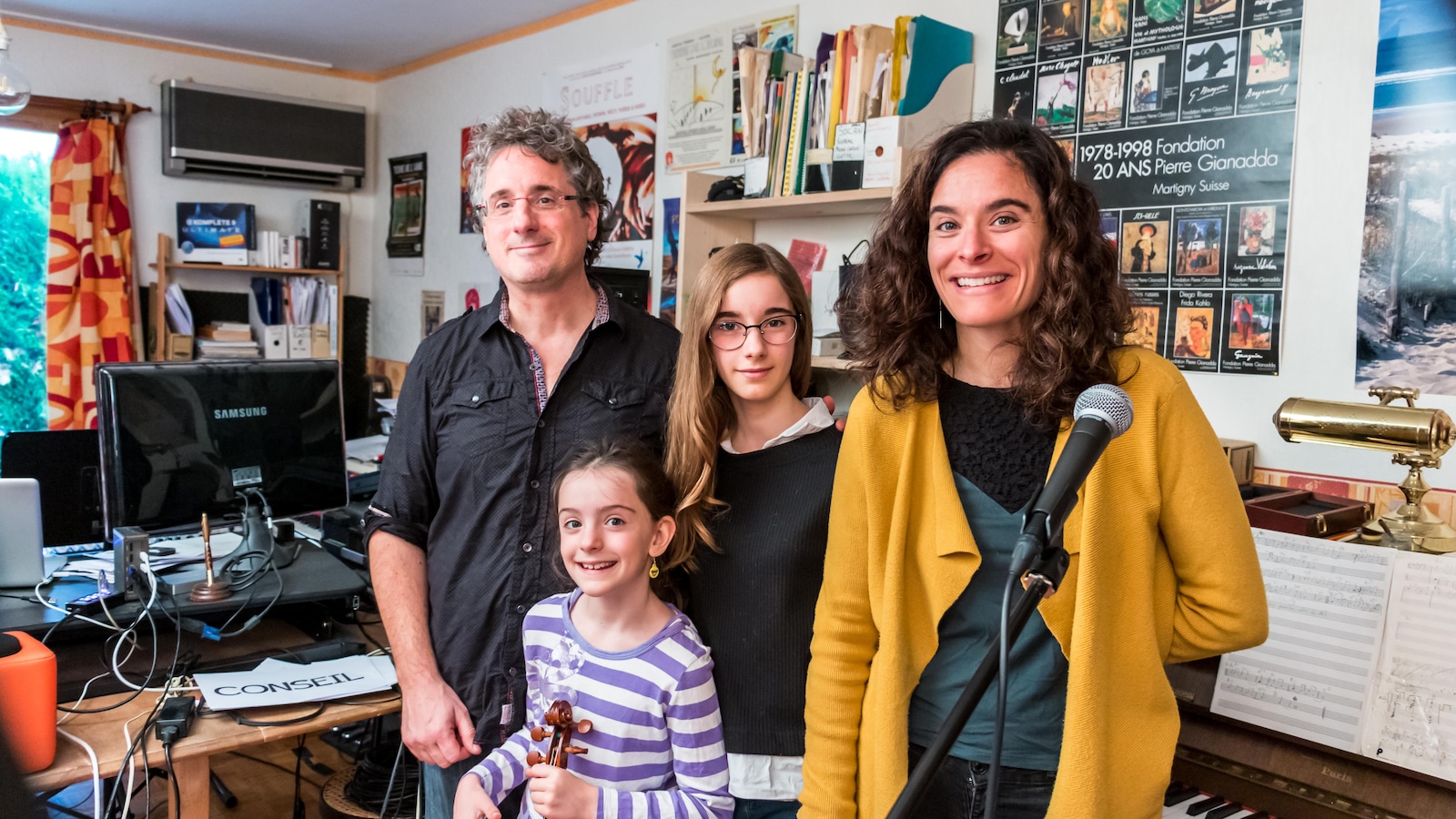 Les quatre membres de la famille dans leur studio à Péage-de-Roussillon, en France, debout près d'un piano et d'un ordinateur