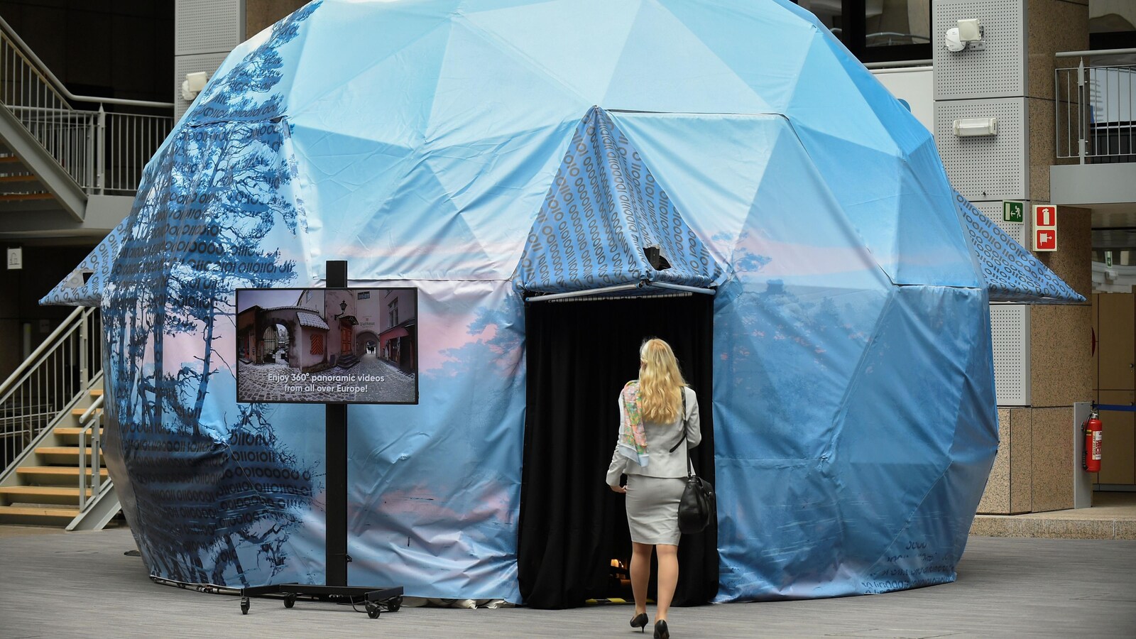 Une femme entre dans une tente en forme d'igloo, haute de quelques mètres.