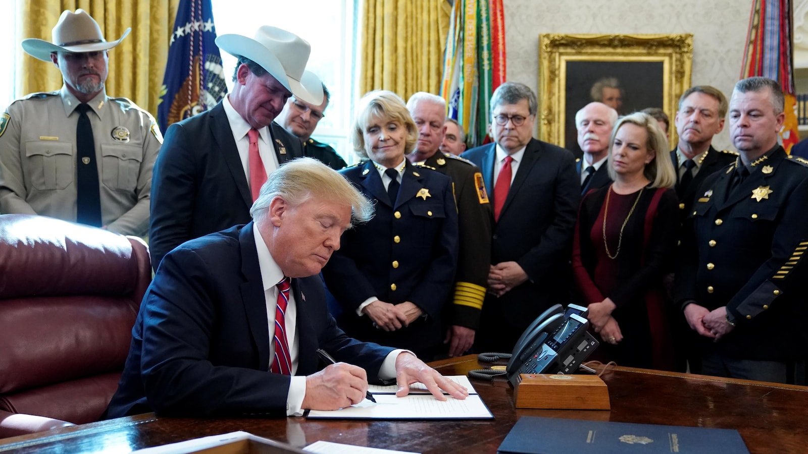 Donald Trump signe un document dans le bureau ovale.