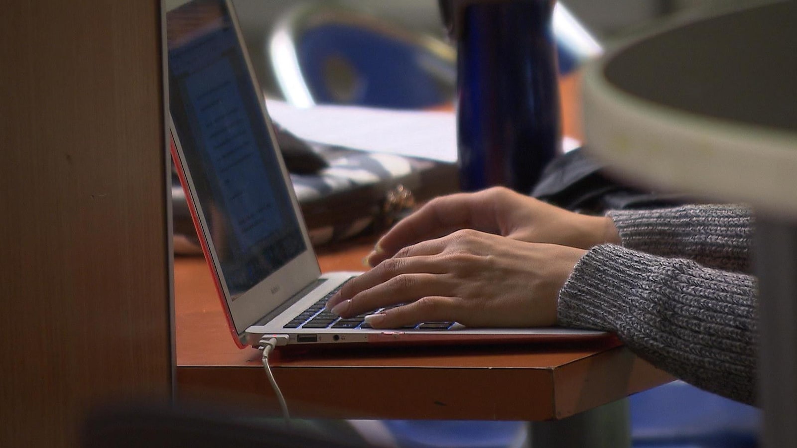 Gros plan sur les mains d'une étudiante qui écrit sur un portable.