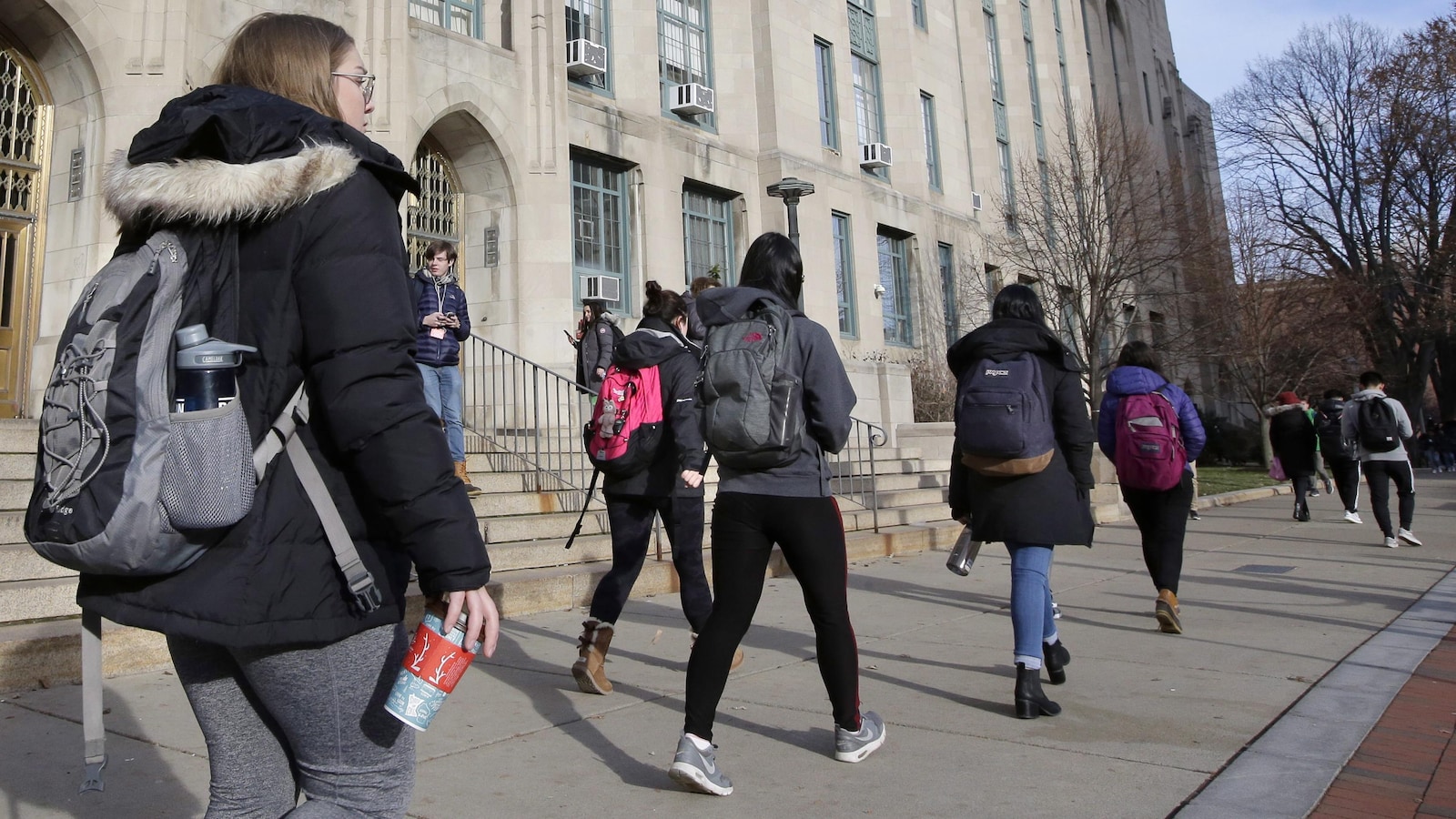 Des étudiants portant des sacs à dos marchent dans un campus universitaire.