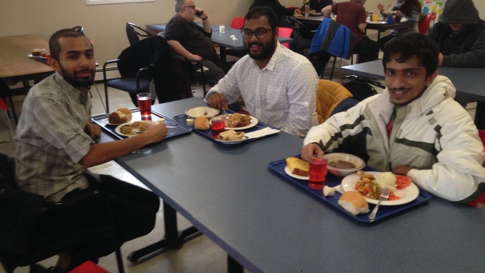 Trois étudiants posés devant leur repas dans une soupe populaire.