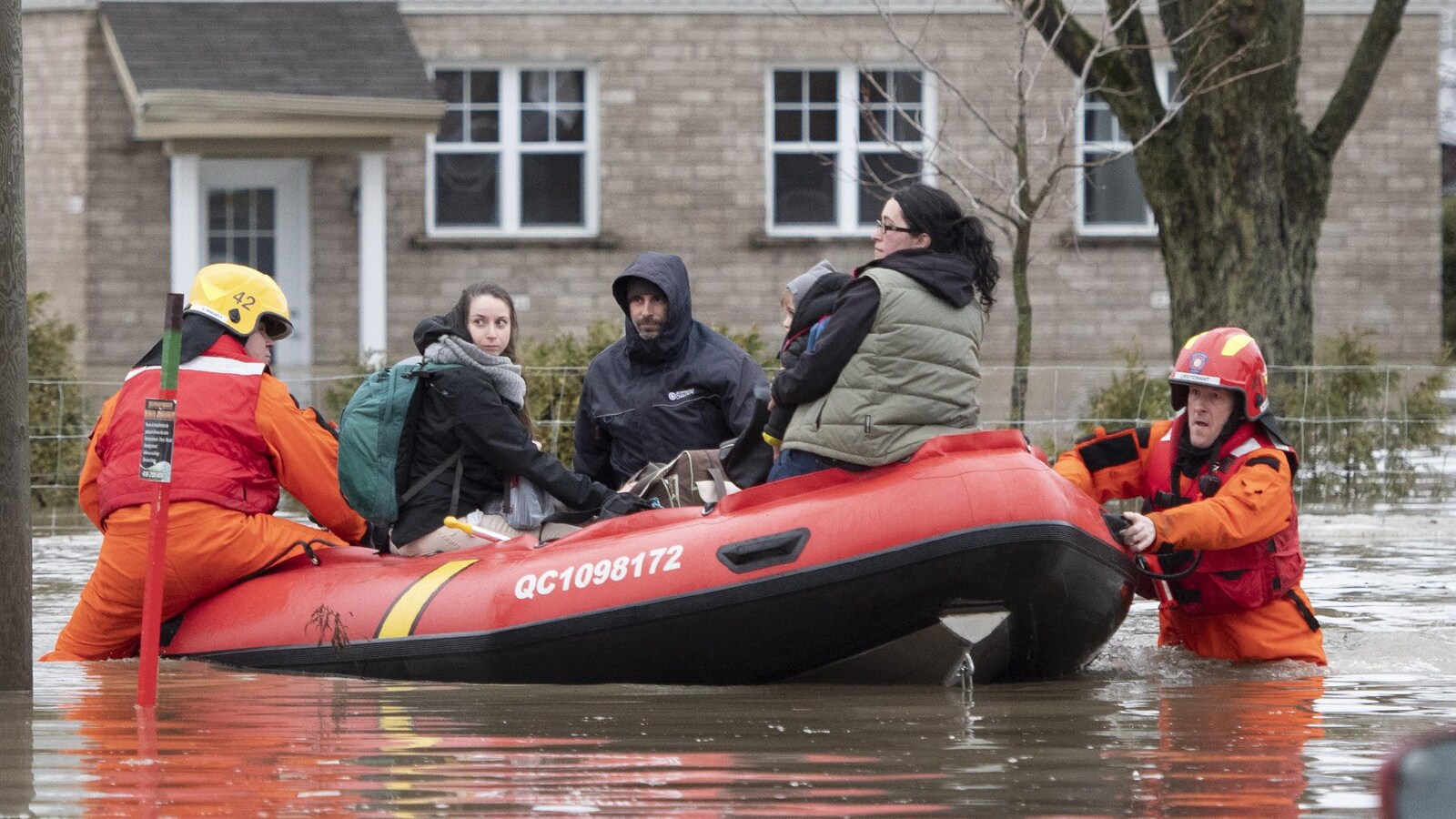 Des citoyens sont évacués par des pompiers dans un bateau.