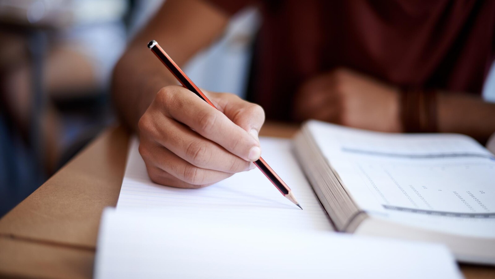 Main d'un étudiant qui prend des notes dans une classe