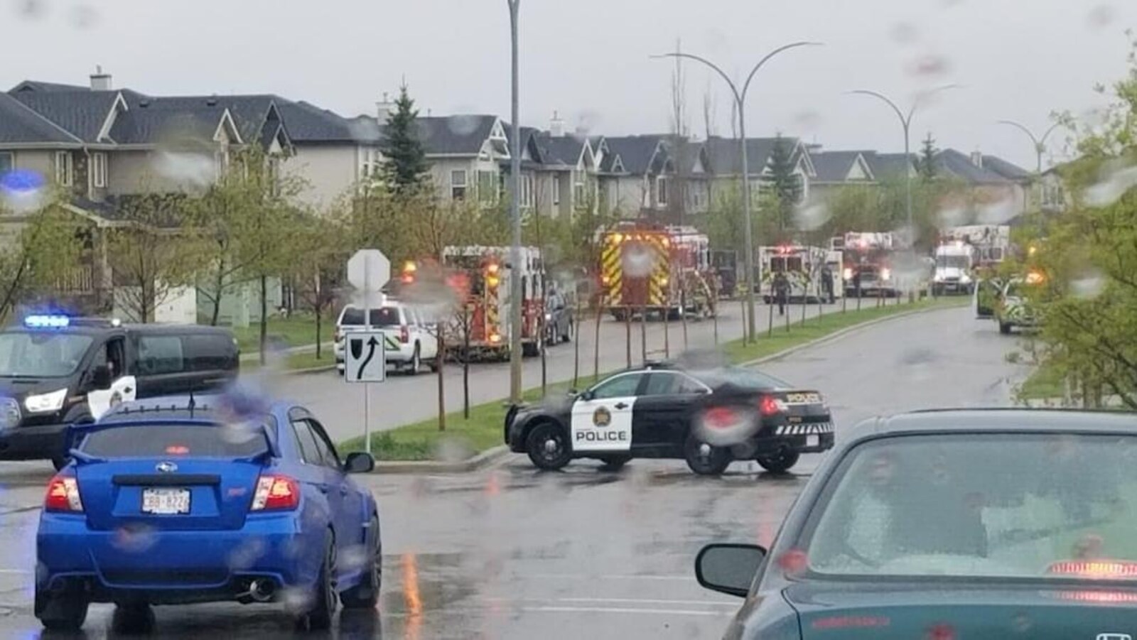 Des véhicules d'urgence garées le long d'une rue sous la pluie.