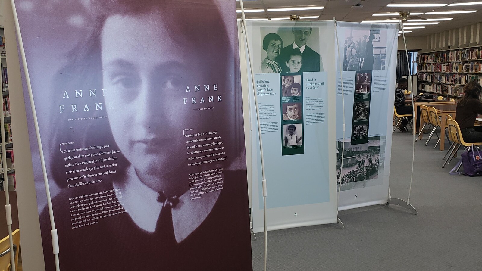 Des panneaux de l'exposition. À lLavant-plan, le panneau montre le visage d'Anne Frank.