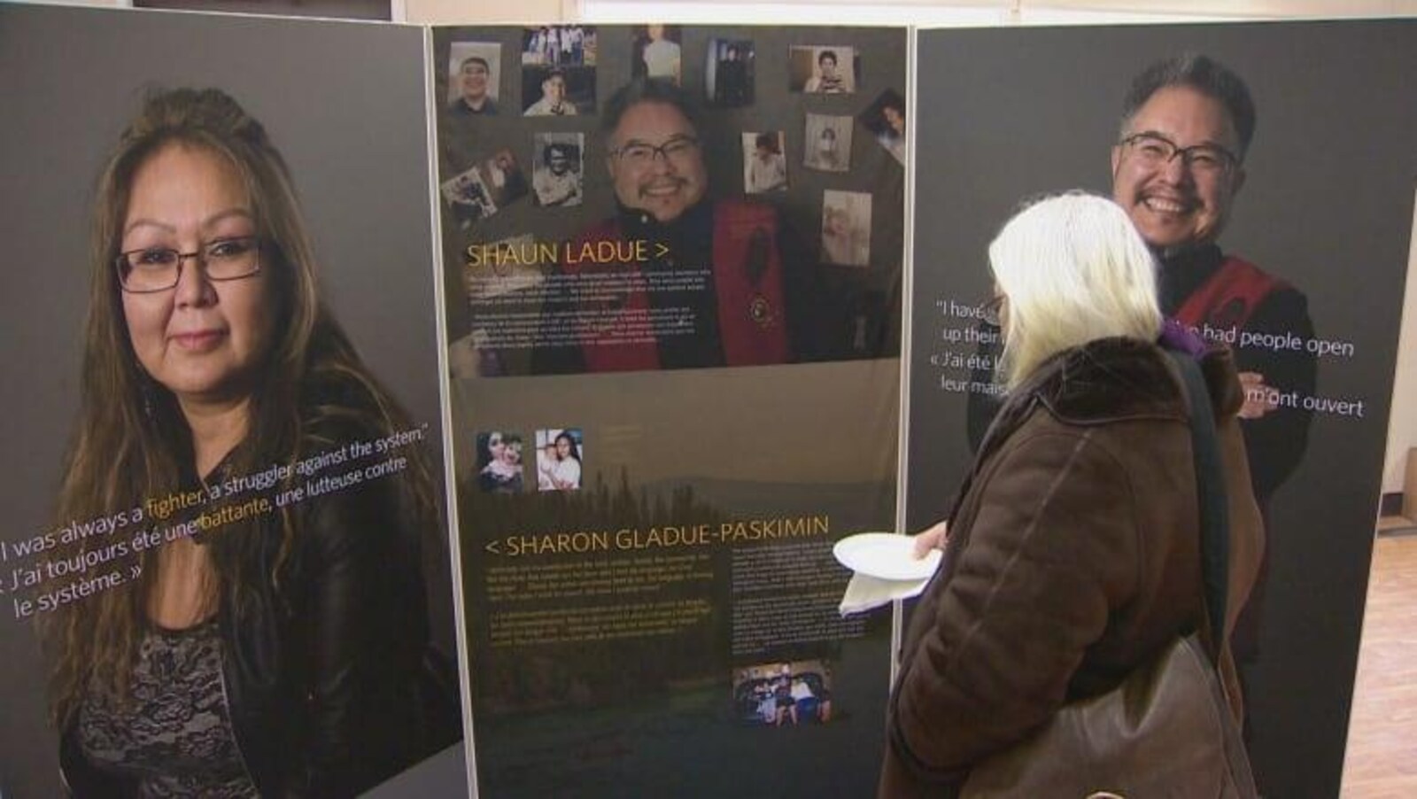 Une femme regarde les panneaux de l'exposition.