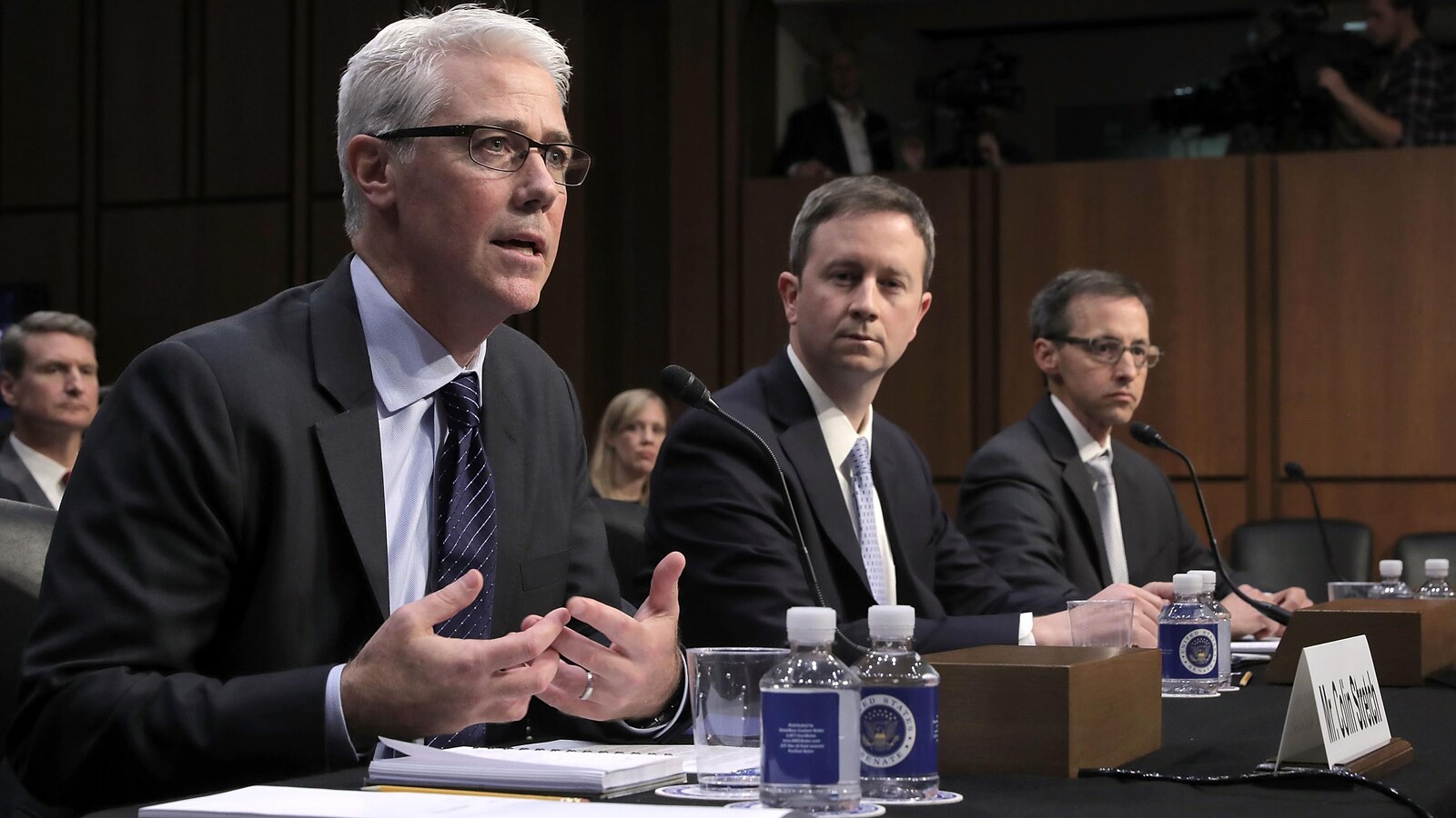 Colin Stretch, Sean Edgett et Richard Salgado, assis derrière une table, devant des micros.
