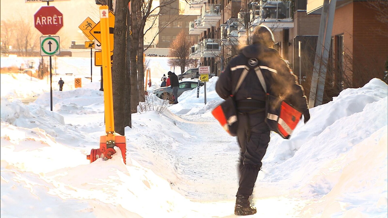 Un facteur livre le courrier dans la neige et le froid.