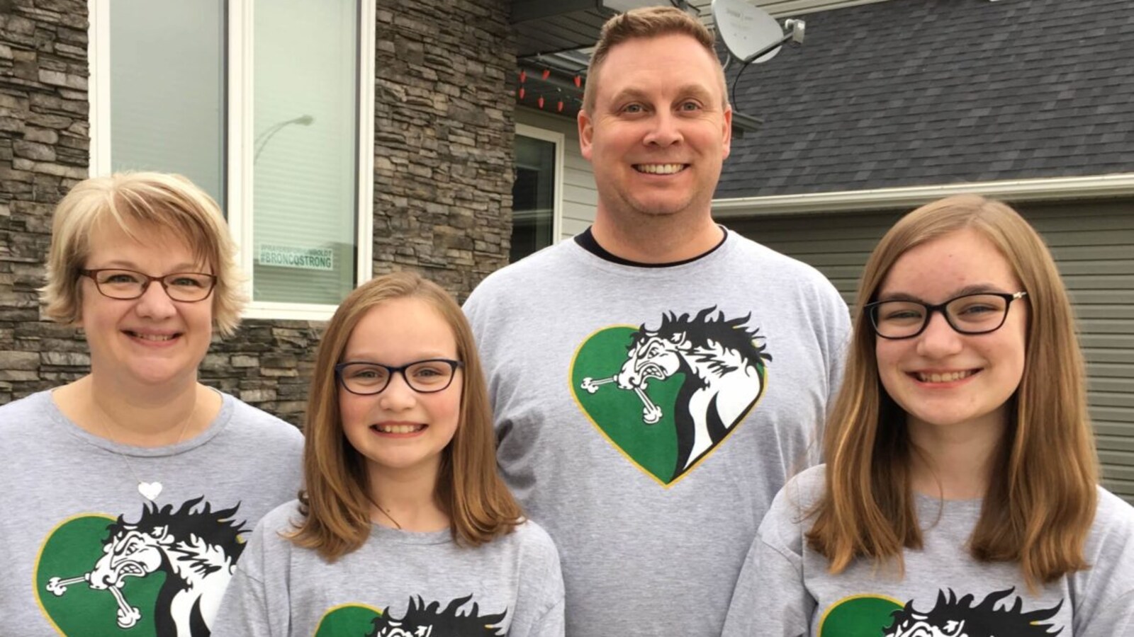 Rene Cannon, son mari ainsi que leurs deux filles, Abbie et Tessa, prennent une photo devant leur maison. Ils sourient et portent des T-shirt à l'éfigie du cheval des Broncos dans un coeur.