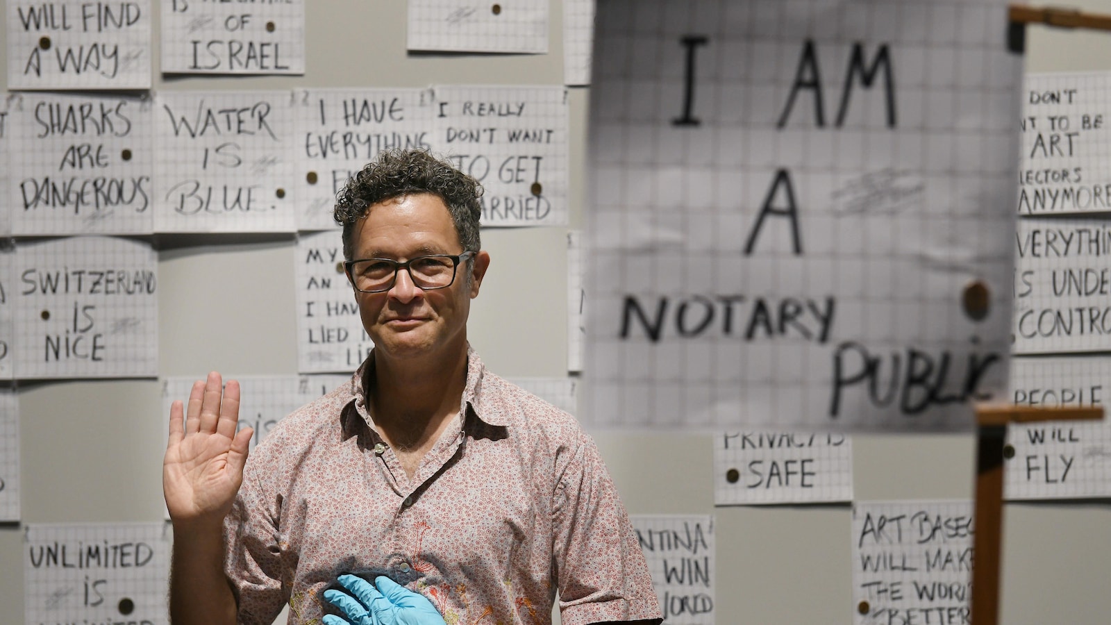 L'artiste américain Paul Ramirez Jonas prend la pose à Art Basel, entouré de papiers rapportant de fausses informations.