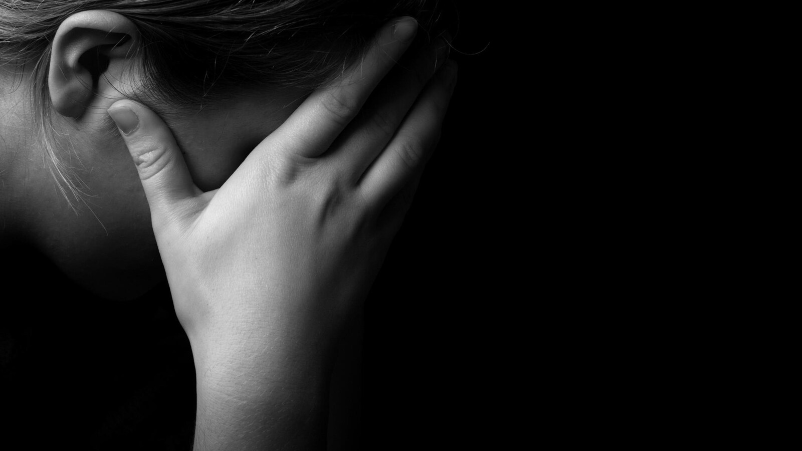 Une femme dans le noir avec sa main sur son oeil.