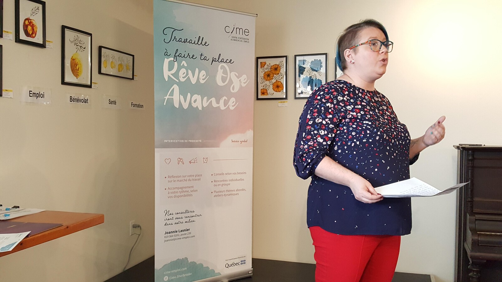 Geneviève Collette devant une bannière du projet Travaille à faire ta place.