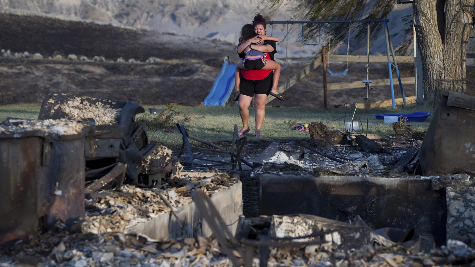 Une mère et sa fille devant les ruines de leur maison de la Première Nation d'Ashcroft, en Colombie-Britannique. Les feux de forêt font rage dans l'intérieur de la province.