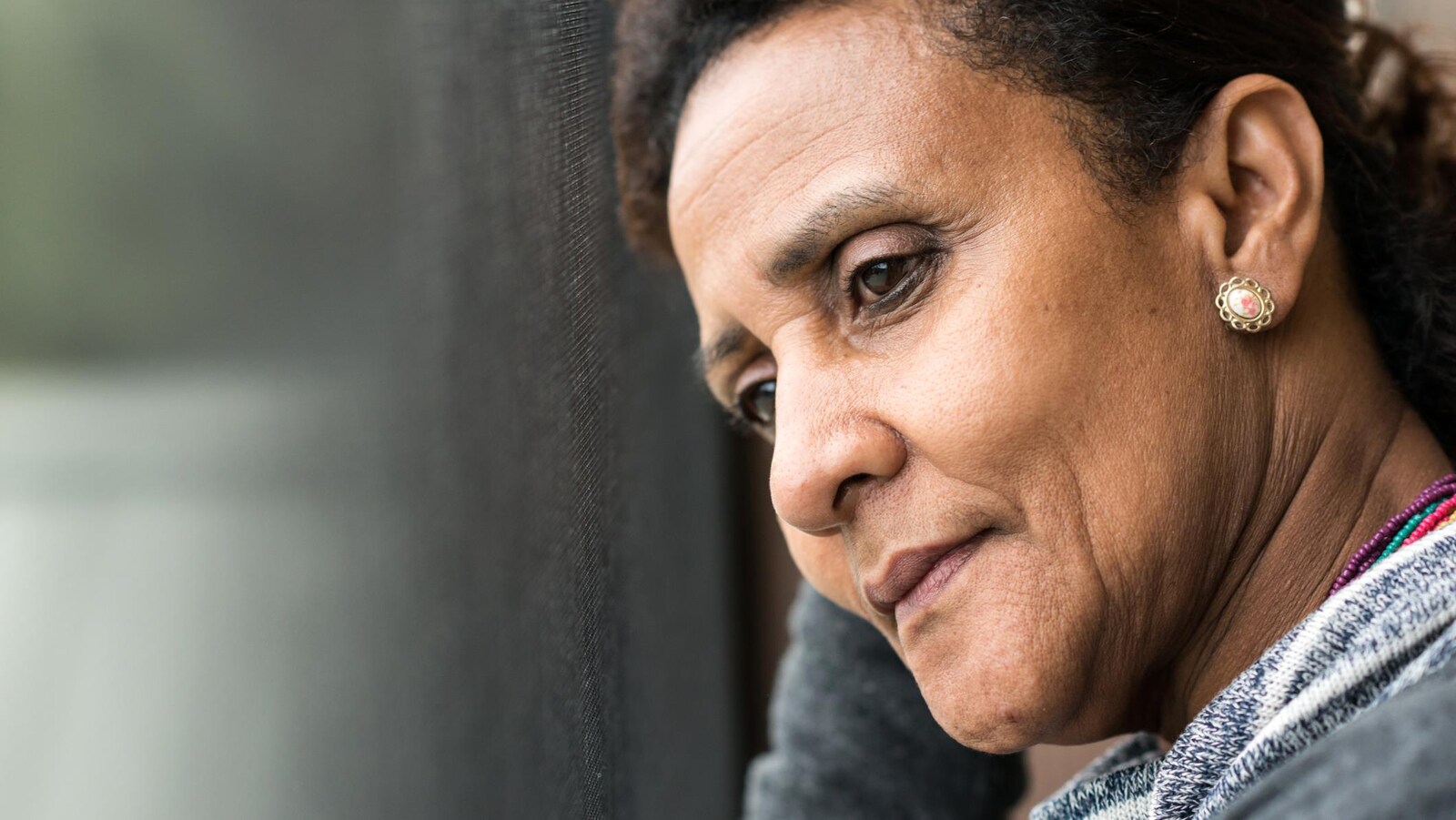 Une femme pensive regarde par la fenêtre.