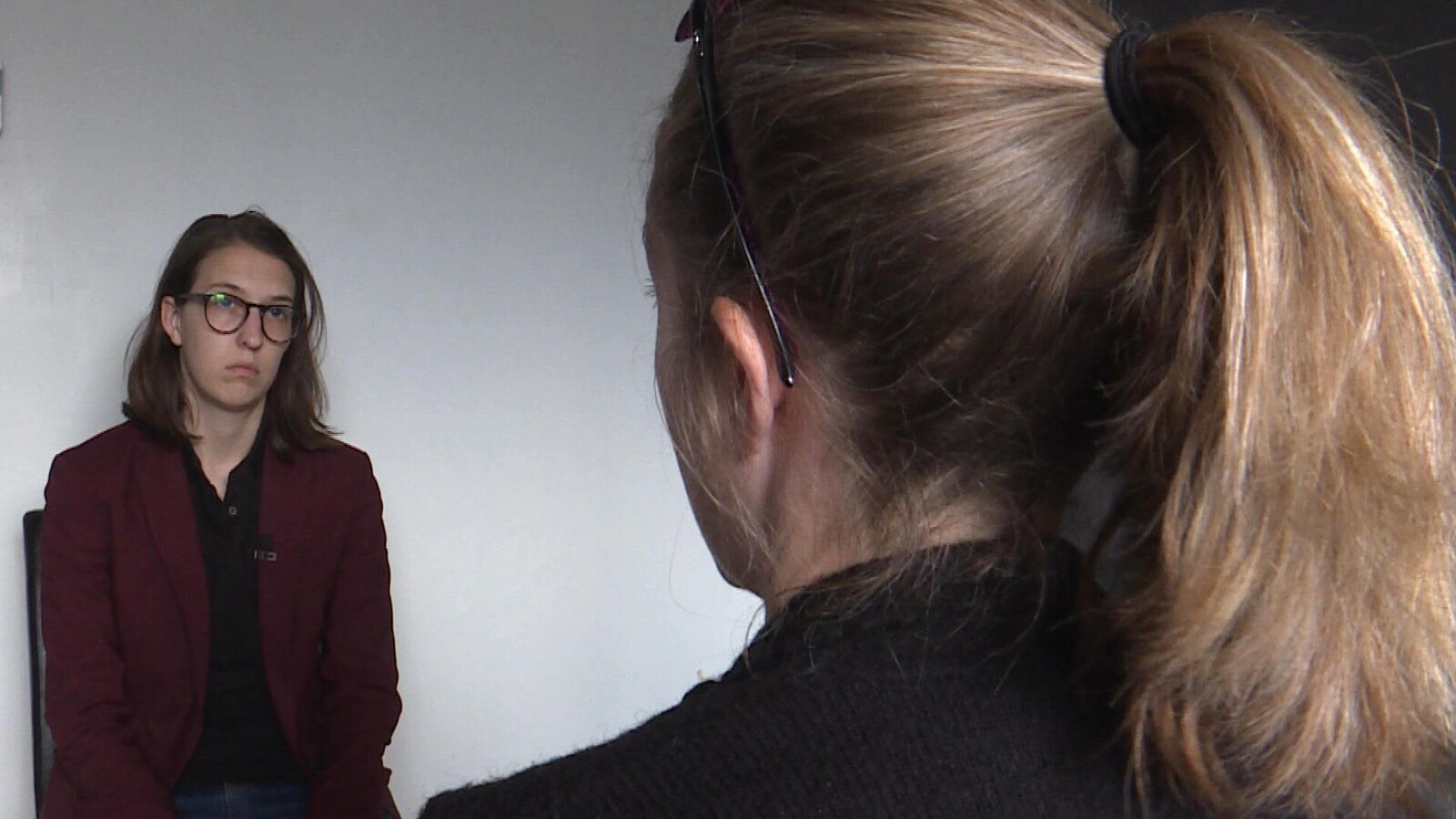 Deux femmes assises se font face; l'une d'elle est vue de dos.