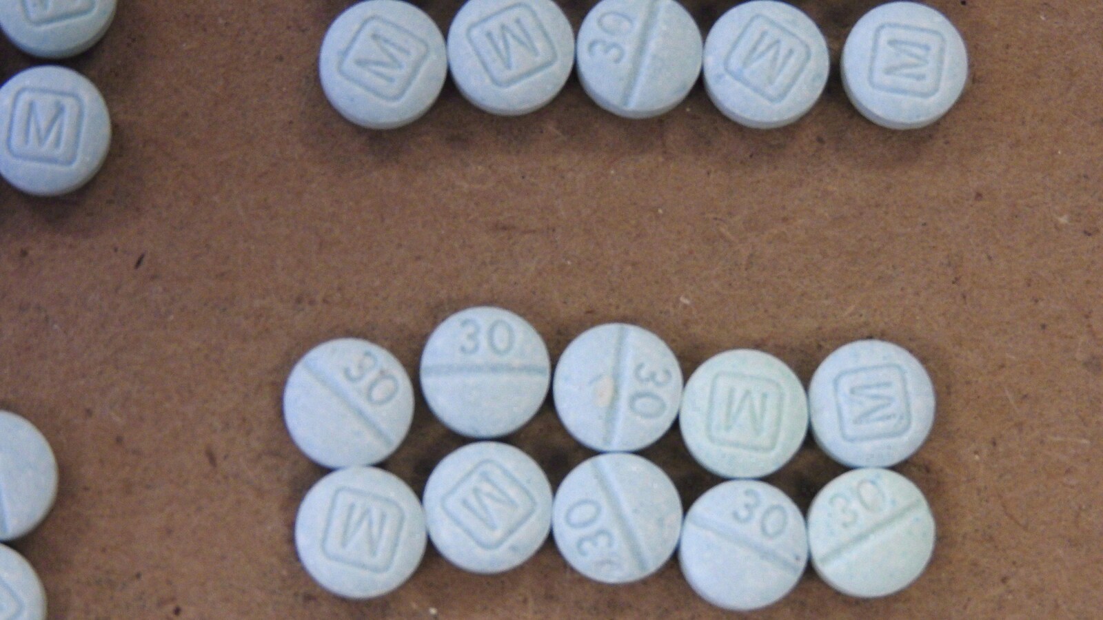 Gros plan sur des pilules de fentanyl. Petites pilules blanches sur lesquelles est inscrit le chiffre 30 et la lettre M.