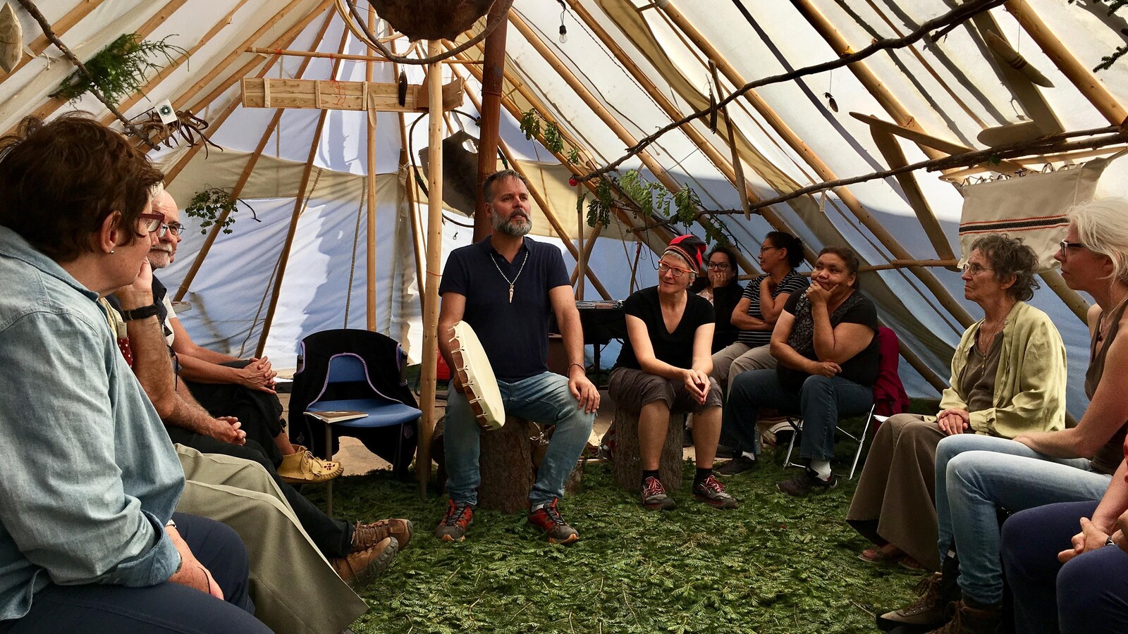 Dans une tente amérindienne, des festivaliers écoutent attentivement un conteur.