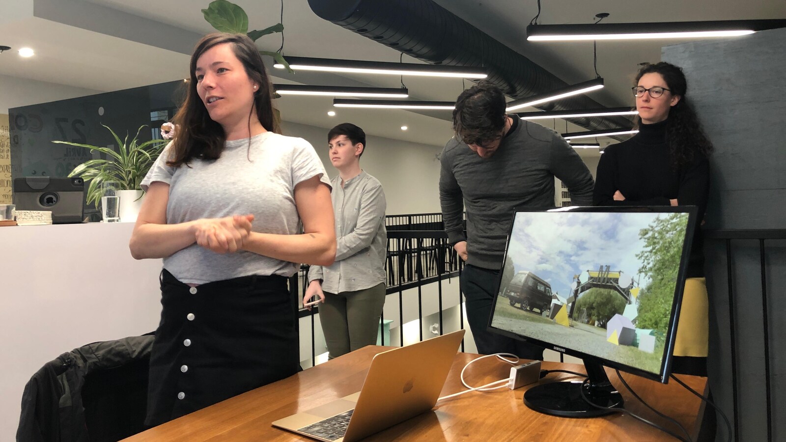Une jeune femme parle lors d'une présentation, appuyée par une projection sur ordinateur.