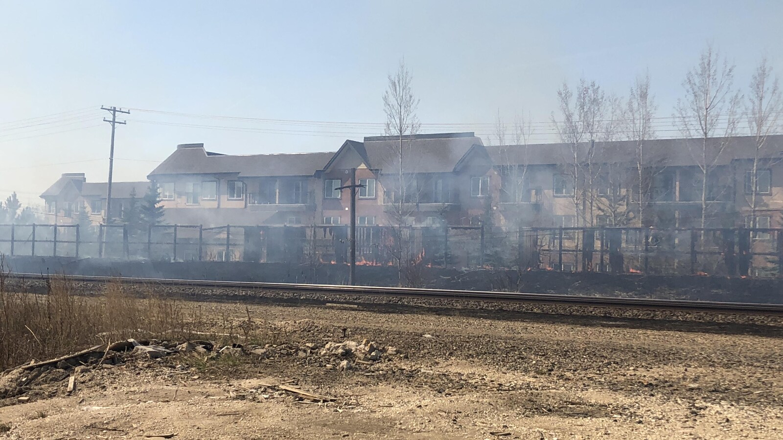 Un feu de brousailles entre des rails et des résidences