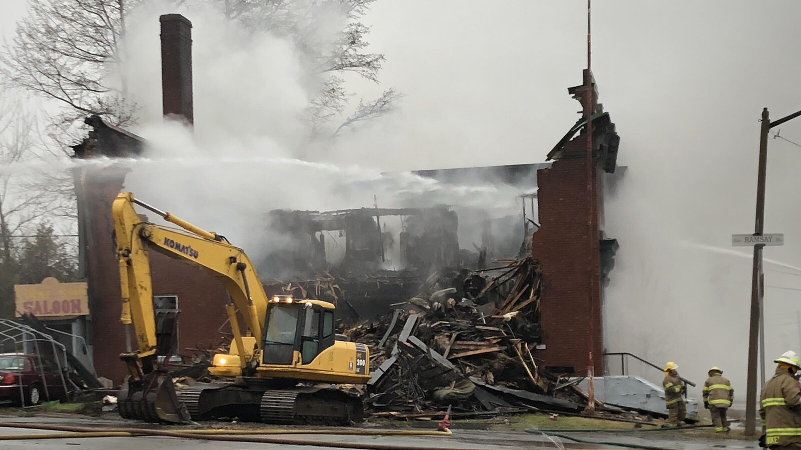 Édifice en briques rouges en feu et la structure est démolie.