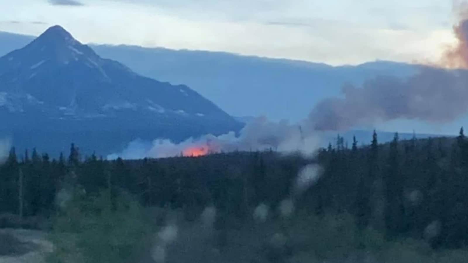 Des flammes visible de loin au pied d'une montagne