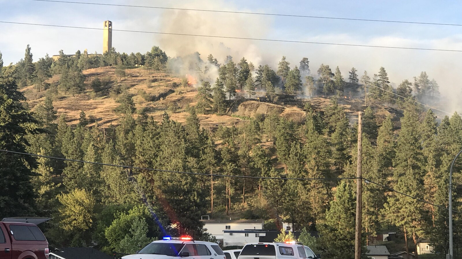 Des flammes se propagent au milieu des arbres le long d'une colline non loin du vignoble Mission Hill à West Kelowna