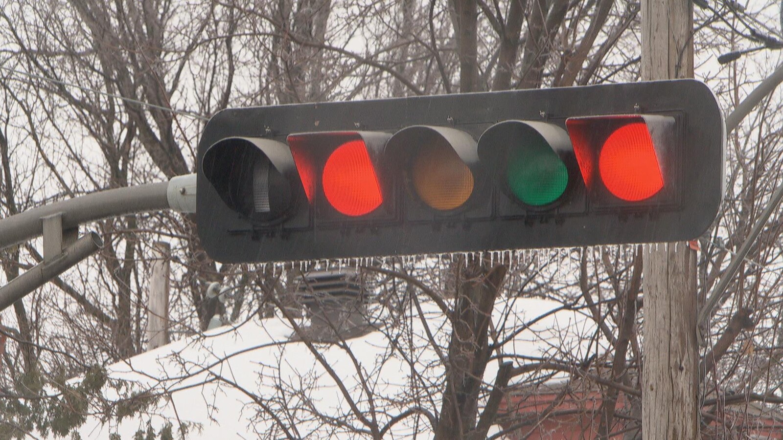 Gros plan d'un feu de circulation au rouge sous lequel se trouvent une quarantaine de petits glaçons.