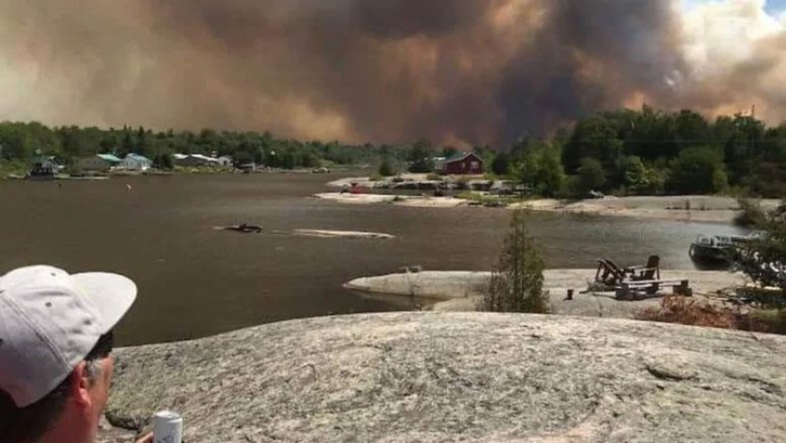 Une épaisse fumée derrière un lac et des arbres.