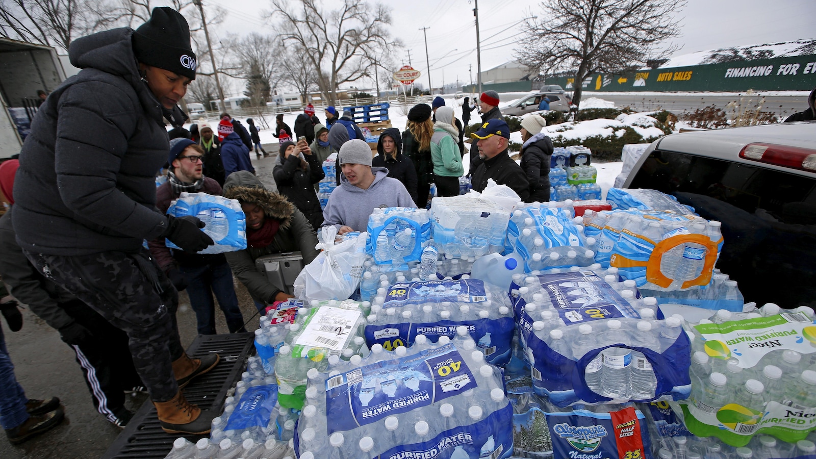 Une personne distribue des caisses d'eau embouteillée.