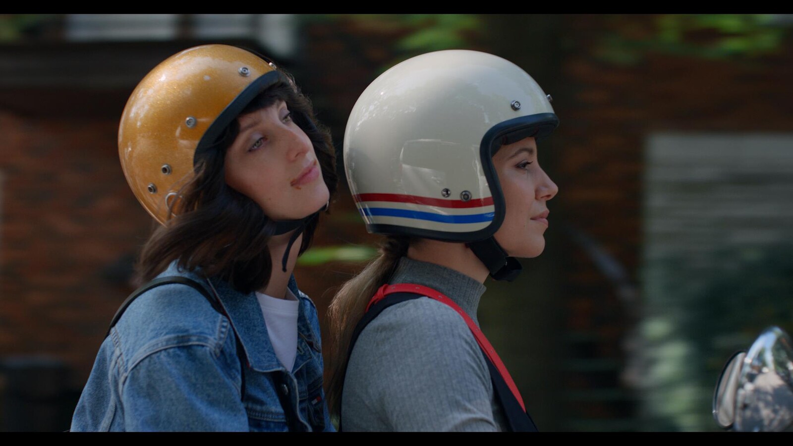 Les deux femmes sont sur un scooter et portent un casque.