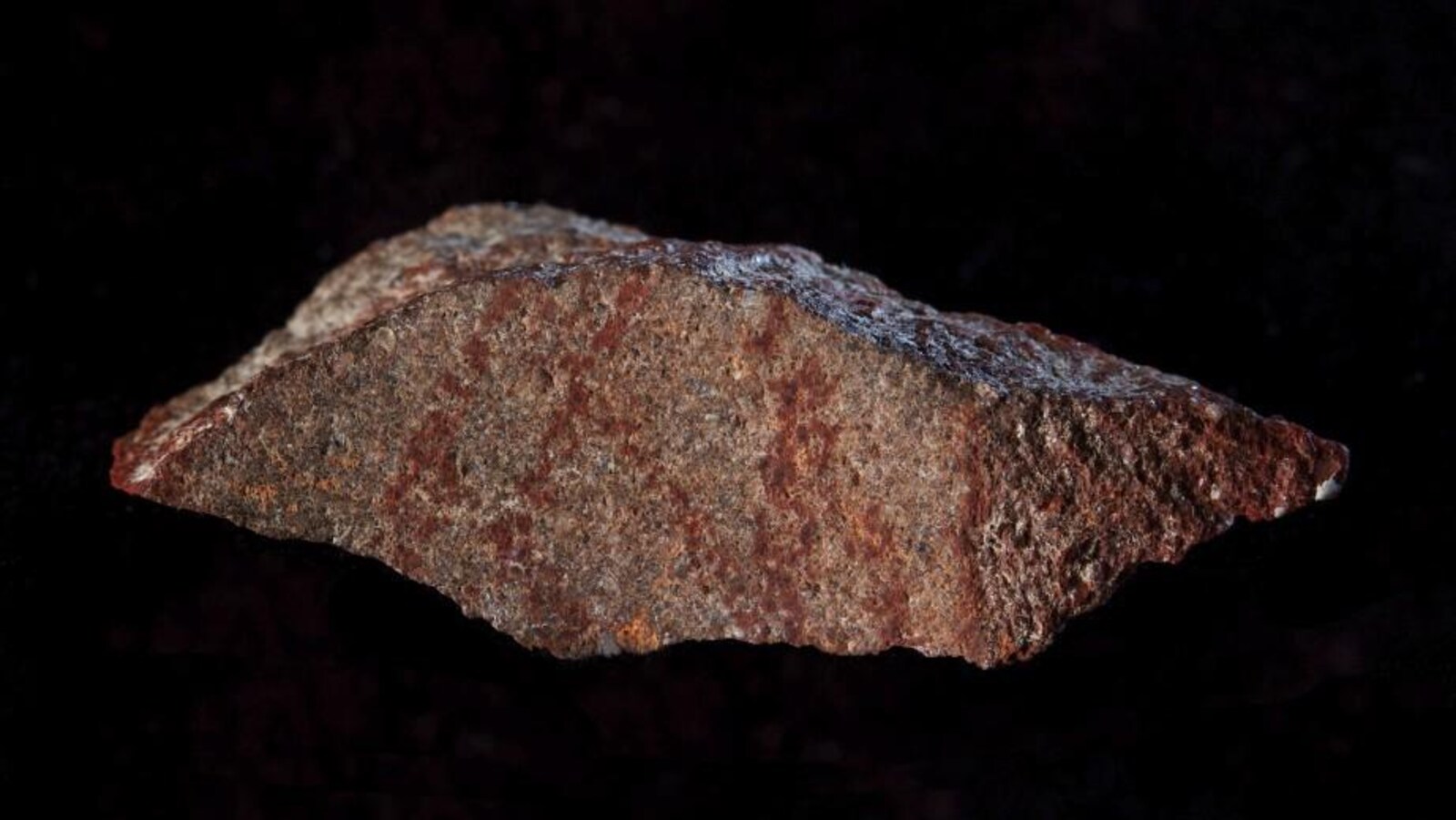 Un fragment de silcrète portant sur l'une de ses faces un dessin composé de neuf lignes tracées au crayon d'ocre.