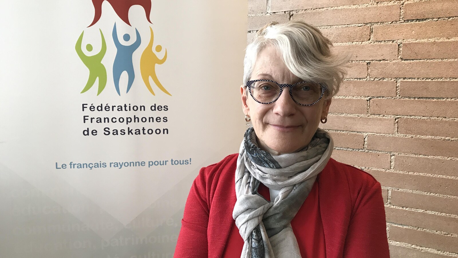 Francine Proulx-Kenzle devant une affiche de la FFS à Saskatoon