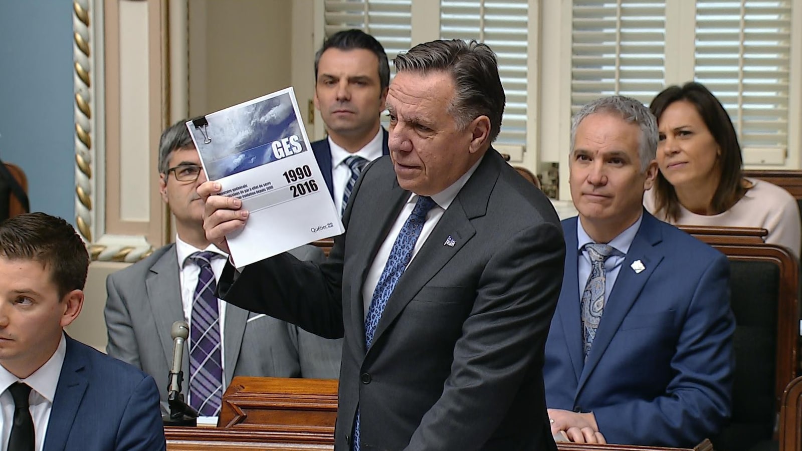 François Legault tient dans ses mains le plus récent bilan des émissions de GES du ministère de l'Environnement.
